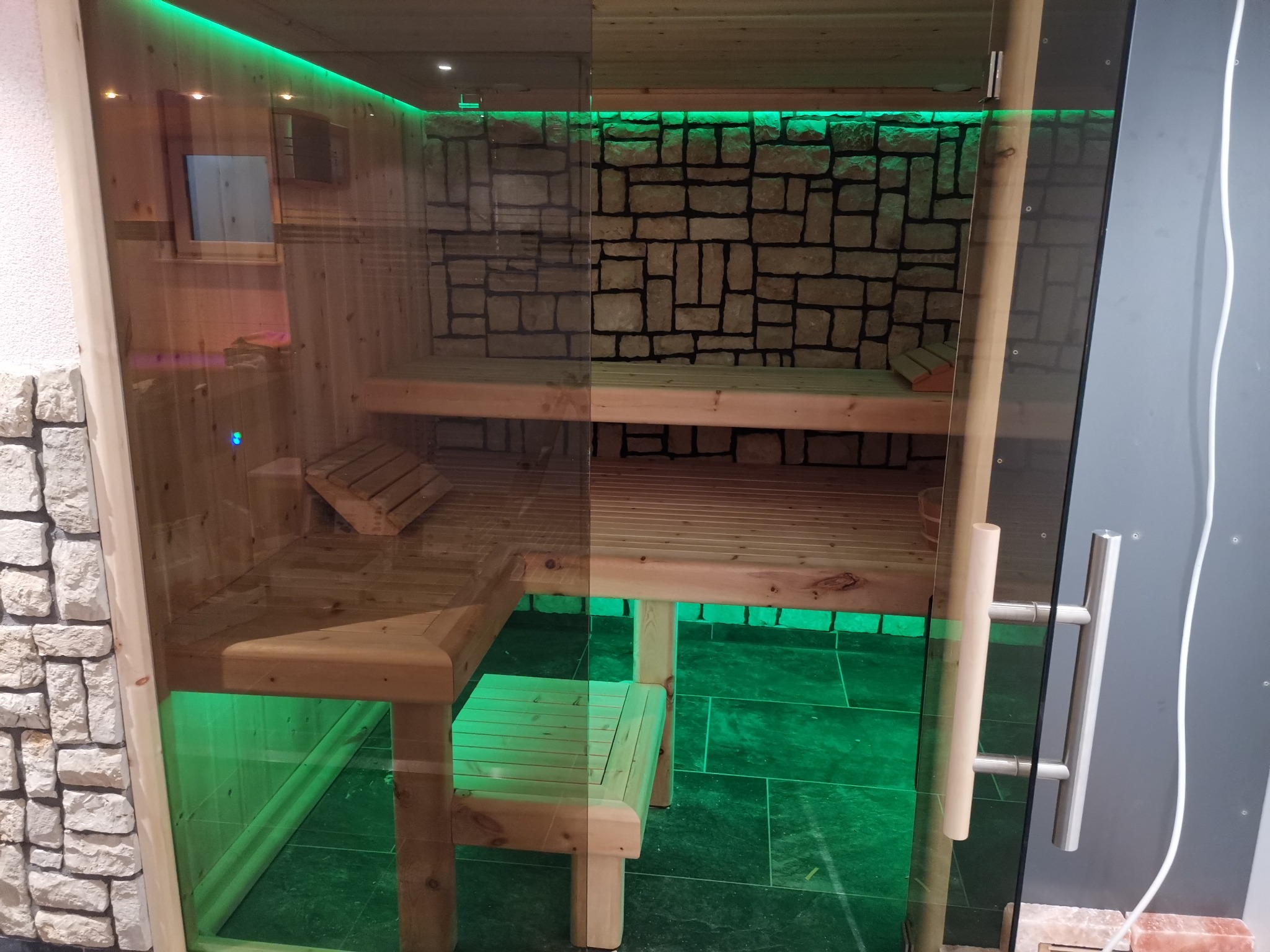 Fertiggestellte individuell gebaute Sauna mit Glasfront und Steinwand